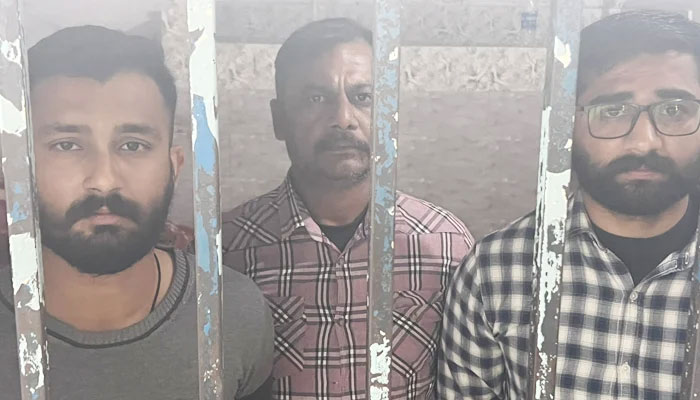 The three cops who shot the youth, Amir Hussain, in Karachi on December 27, 2022, stand behind bars at a police station. — Geo News/Afzal Nadeem Dogar