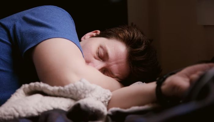 Image shows a man sleeping on his arm.— Unsplash