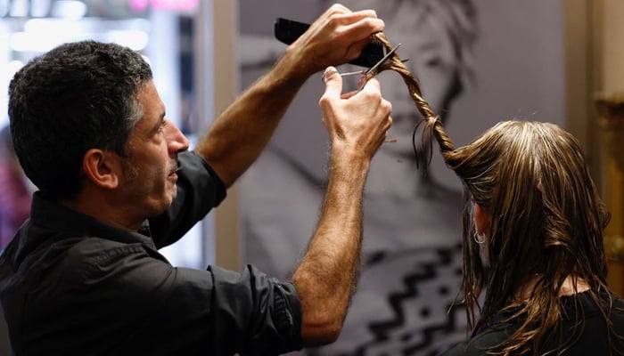 Belgian hairdresser cuts a customers hair, which will be collected by Dung Dung —REUTERS