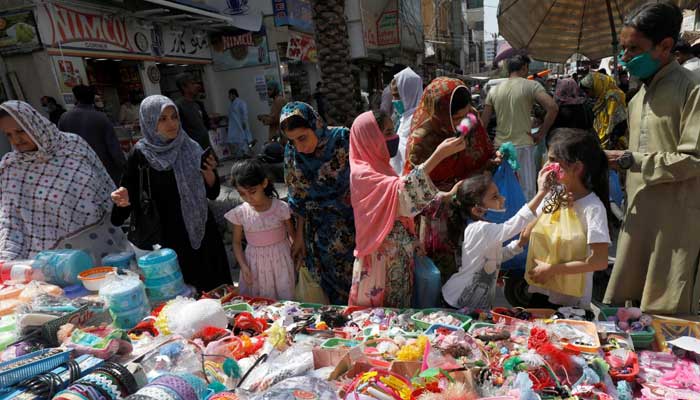 11 مئی 2020 کو کراچی کے ایک بازار میں خواتین اور بچے ایک اسٹال سے خریداری کر رہے ہیں۔ – رائٹرز