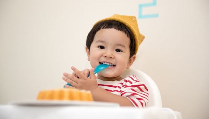 A baby boy biting a plastic spoon.— Unsplash