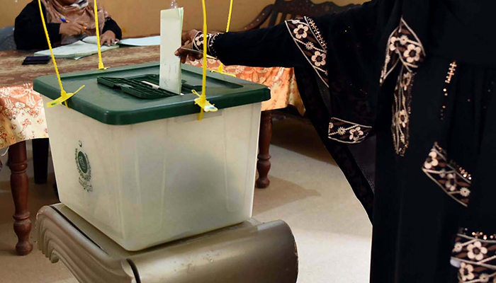 A woman casts her vote at a polling station during by-elections in Karachi on October 16, 2022. — PPI