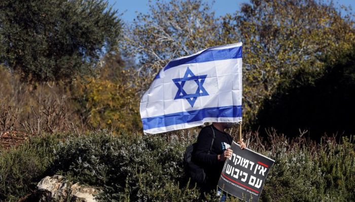 A man holds the national flag of Israel and a sign that says in Hebrew There is no democracy if there is occupation at a protest outside the Knesset, Israels parliament, on the day the new right-wing government is sworn in, with Benjamin Netanyahu as Prime Minister, in Jerusalem December 29, 2022.— Reuters