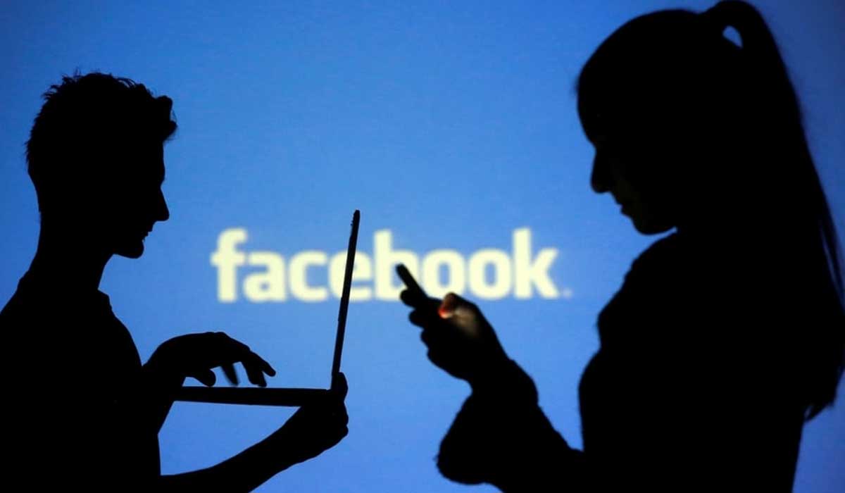 A woman and a man use laptops with Facebooks logo in the background. — Reuters