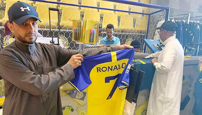 Seorang penggemar memegang kaus bertuliskan nama Ronaldo dan nomor 7, di toko Saudi Al Nassr FC di ibu kota Saudi, Ryadh, pada 31 Desember 2022. — AFP