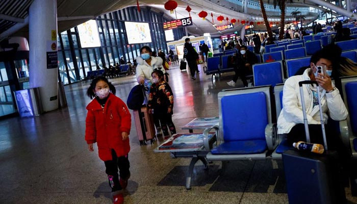 Seorang anak berjalan sementara orang menunggu dengan barang bawaan mereka di stasiun kereta api, di tengah wabah penyakit coronavirus (COVID-19), di Wuhan, provinsi Hubei, Cina 1 Januari 2023. — Reuters