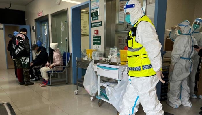 A security personnel in a protective suit keeps watch as medical workers attend to patients at the fever department of Tongji Hospital, a major facility for patients of the coronavirus disease (COVID-19), in Wuhan, Hubei province, China January 1, 2023. — Reuters