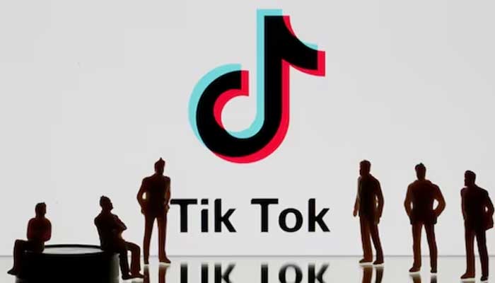 Illustration of people standing against the backdrop of TikToks logo. — Reuters/File