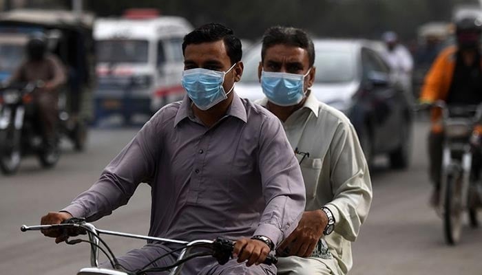 The picture shows two men riding a motorcycle wearing masks. — AFP/File