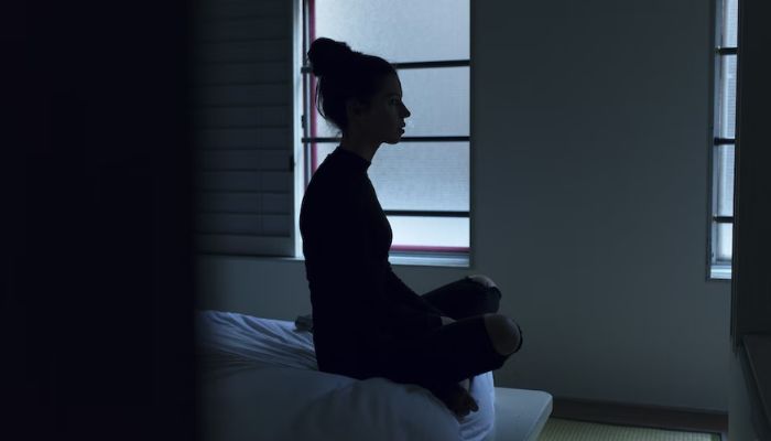 A woman sitting on a bed. Unsplash