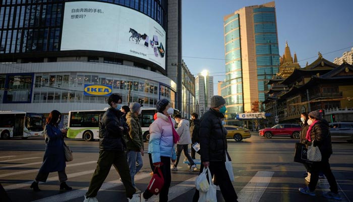 People wearing protective masks cross a street as China returns to work despite continuing coronavirus disease (COVID-19) outbreaks in Shanghai, China, January 3, 2023. — Reuters