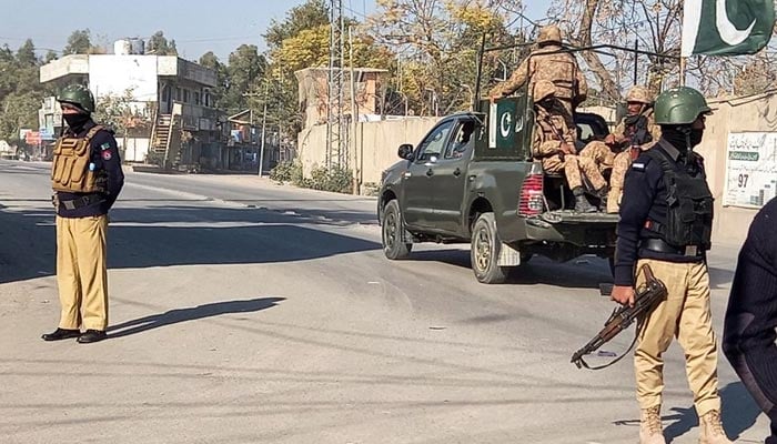 An Army vehicle patrols, past police officers stand guard along a road, near cantonment area in Bannu, Pakistan December 21, 2022. — Reuters