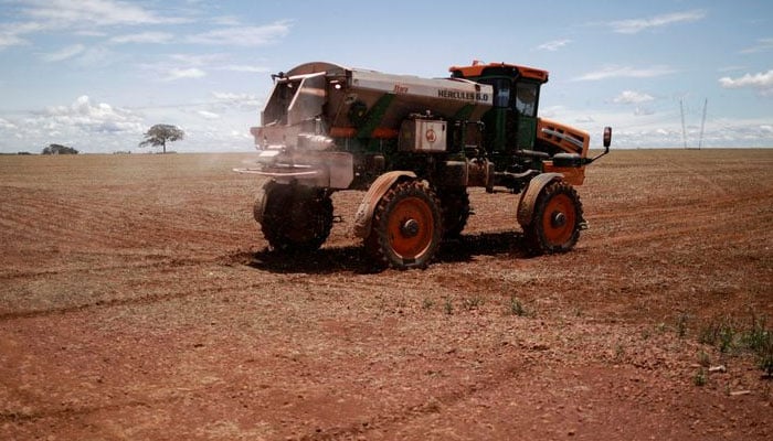 An agricultural worker drives a tractor spreading fertiliser in a soybean field, near Brasilia, Brazil —Reuters/File