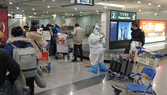 Passengers arriving on international flights wait in line next to a staff member wearing personal protective equipment (PPE) at the airport in Chengdu, China January 6, 2023.— Reuters