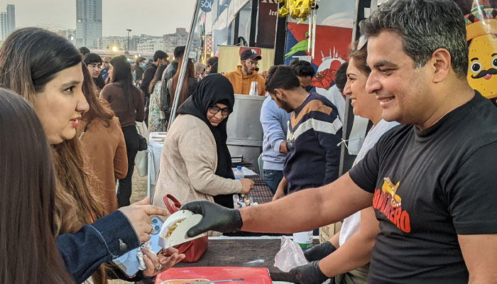 کراچی ایٹ فیسٹیول میں ایک دکاندار ایک گاہک کو ٹیکو دے رہا ہے۔  - رپورٹر