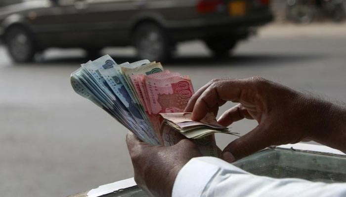 A money changer counts Pakistani Rupee (PKR) notes in Karachi September 23, 2009. — Reuters/File