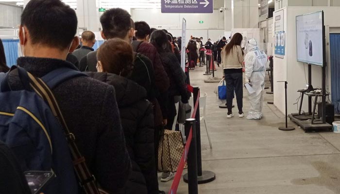 Passengers arriving on international flights wait in line next to a police officer wearing personal protective equipment (PPE) and speaking with a woman at the airport in Chengdu, China January 6, 2023. — Reuters