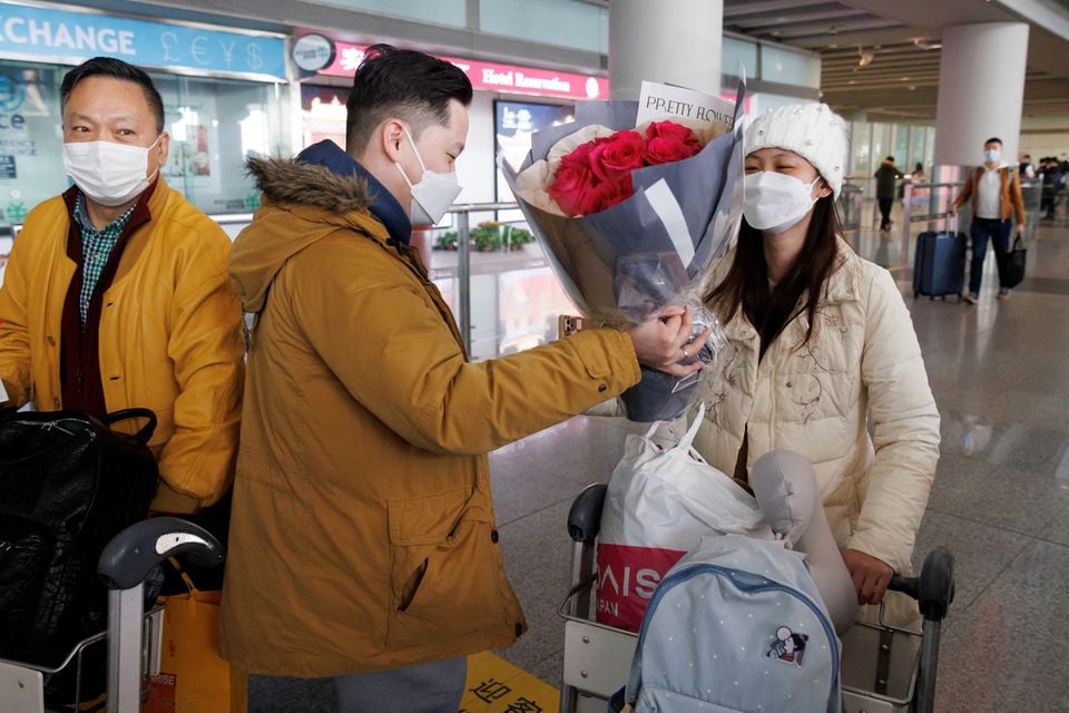 A man hands flowers to a woman after she came through the international arrivals gate at Beijing Capital International Airport in Beijing, January 8, 2023.— Reuters