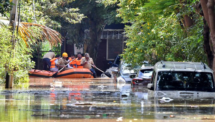 Members of a rescue team row their boat past submerged vehicles following torrential rains in Bengaluru, India. — Reuters/File