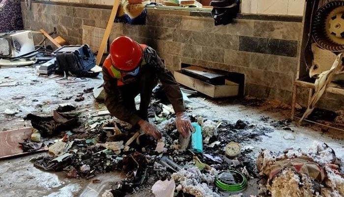 A rescue worker amongst the remains of a madrassah in Peshawar after it was attacked on October 27 2020. — AFP