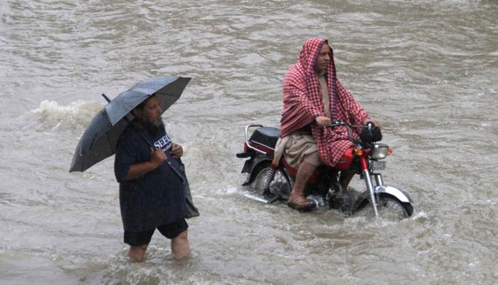 A man holds an umbrella as he walks through floodwaters during heavy rain in Lahore, Pakistan. — Reuters/File