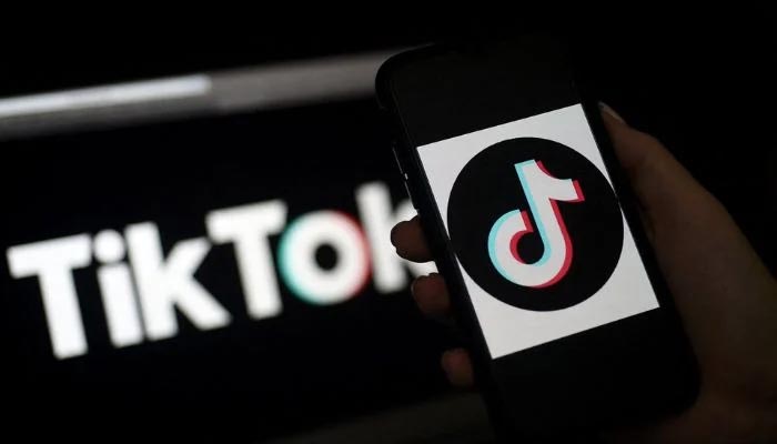 A mobile phone user shows the TikTok logo on an iPhone, against the logo of the app in Arlington, Virginia on April 13, 2020.— AFP