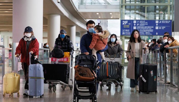 Passengers push their luggage through the international arrivals hall at Beijing Capital International Airport. — Reuters