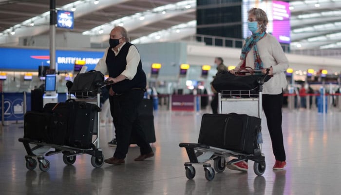 Passengers wearing facemasks walk at Heathrow Airport in London, Britain on June 10, 2021. — Reuters