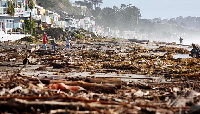 People walk amid storm debris washed up on the beach on January 10, 2022 in Aptos, California. — AFP