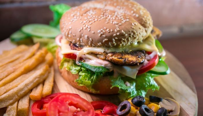 A chicken burger with fries and side vegetables.— Unsplash