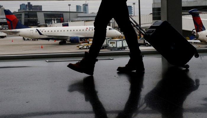 A passenger walks past a Delta Airlines plane at a gate at Logan International Airport in Boston, Massachusetts, US, January 3, 2022. — Reuters
