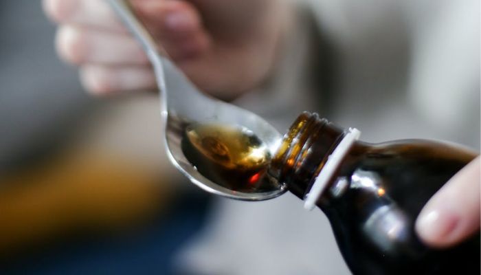 A Person Holding a Spoon with Cough Syrup.— Pexels