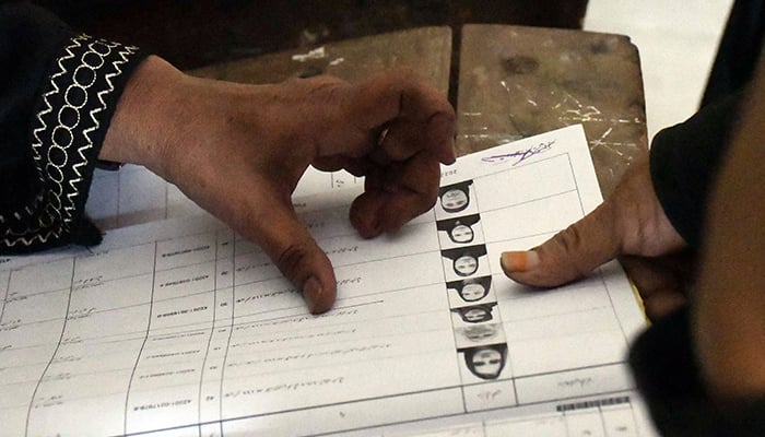 15 جنوری 2023 کو کراچی میں بلدیاتی انتخابات کے دوران ایک پولنگ اسٹیشن پر ووٹ ڈالنے سے پہلے ایک خاتون ووٹر نے انمٹ سیاہی سے اپنے انگوٹھے کی شناخت کی تصدیق کی۔ — آن لائن