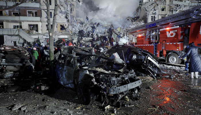 A destroyed car and a residential building hit by a missile strike in Dnipro.— AFP