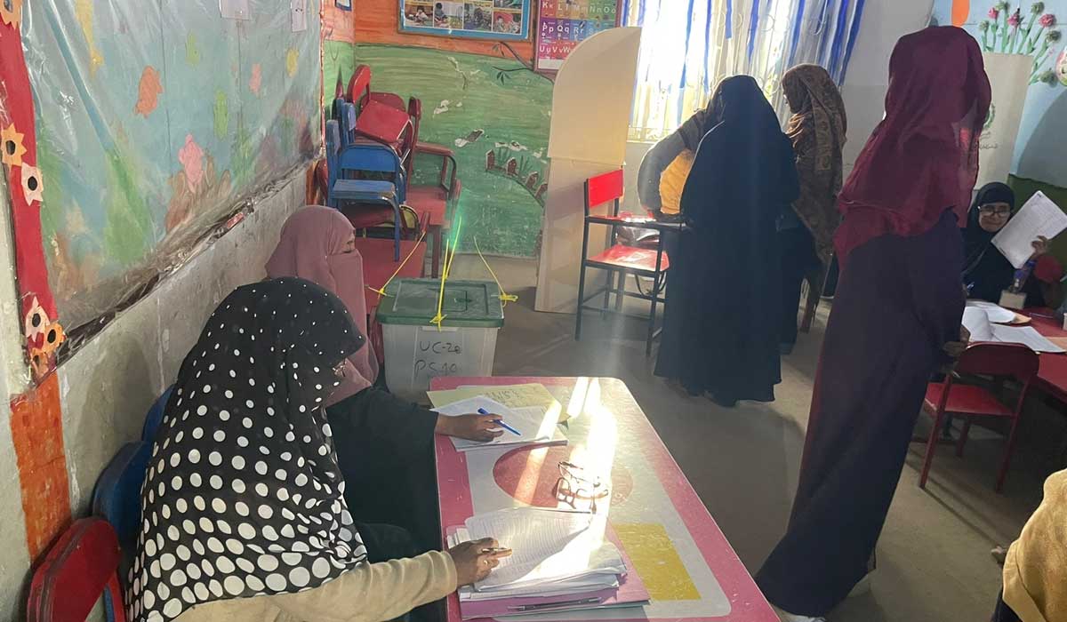 Staf pemungutan suara memandu pemilih perempuan dalam melakukan proses pemungutan suara di Karachi.  — Geo.tv/Rana Jawaid