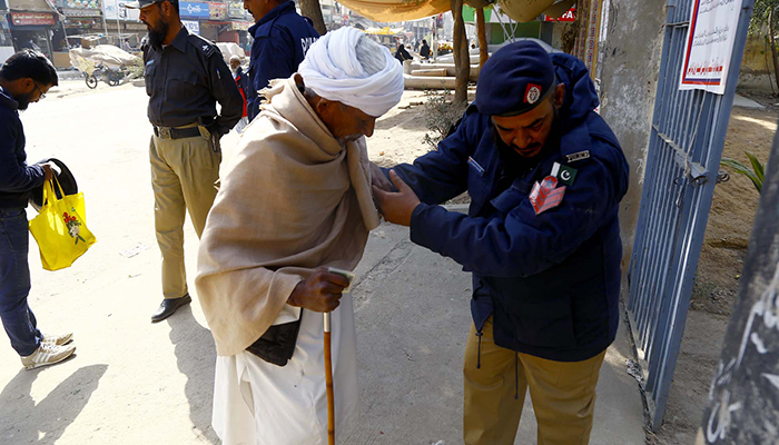 Petugas keamanan memeriksa seorang lanjut usia sebelum mengizinkannya memasuki TPS selama tahap kedua pemilihan pemerintah daerah di sebuah TPS di Karachi pada 15 Januari 2023. — PPI