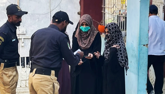 15 جنوری 2023 کو مقامی حکومتوں کے انتخابات کے دوران ایک پولیس اہلکار کراچی میں پولنگ اسٹیشن کے باہر خواتین ووٹرز کے کاغذات چیک کر رہا ہے۔ — Geo.tv