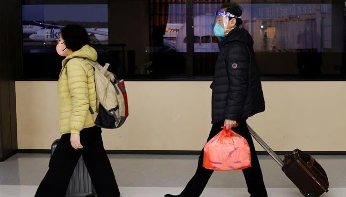 چین کے دالیان سے ایک ہوائی جہاز کے مسافر، 12 جنوری 2023 کو جاپان کے ٹوکیو کے مشرق میں ناریتا کے ناریتا بین الاقوامی ہوائی اڈے پر پہنچنے پر کورونا وائرس کی بیماری (COVID-19) کے ٹیسٹ ایریا کی طرف جاتے ہیں۔ — رائٹرز