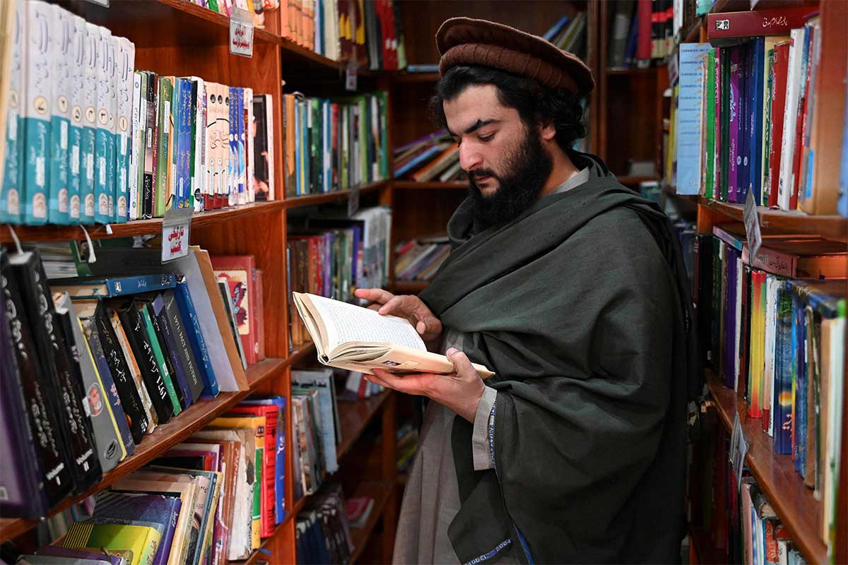 Hakimullah Afridi flips through pages inside the library. — AFP