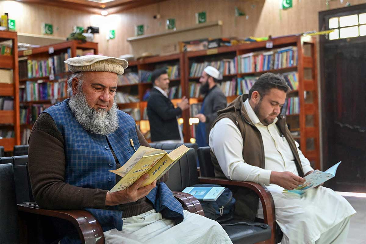 Seorang warga Irfanullah Khan (kiri) membaca buku di perpustakaan Darra Adam Khel.  —AFP