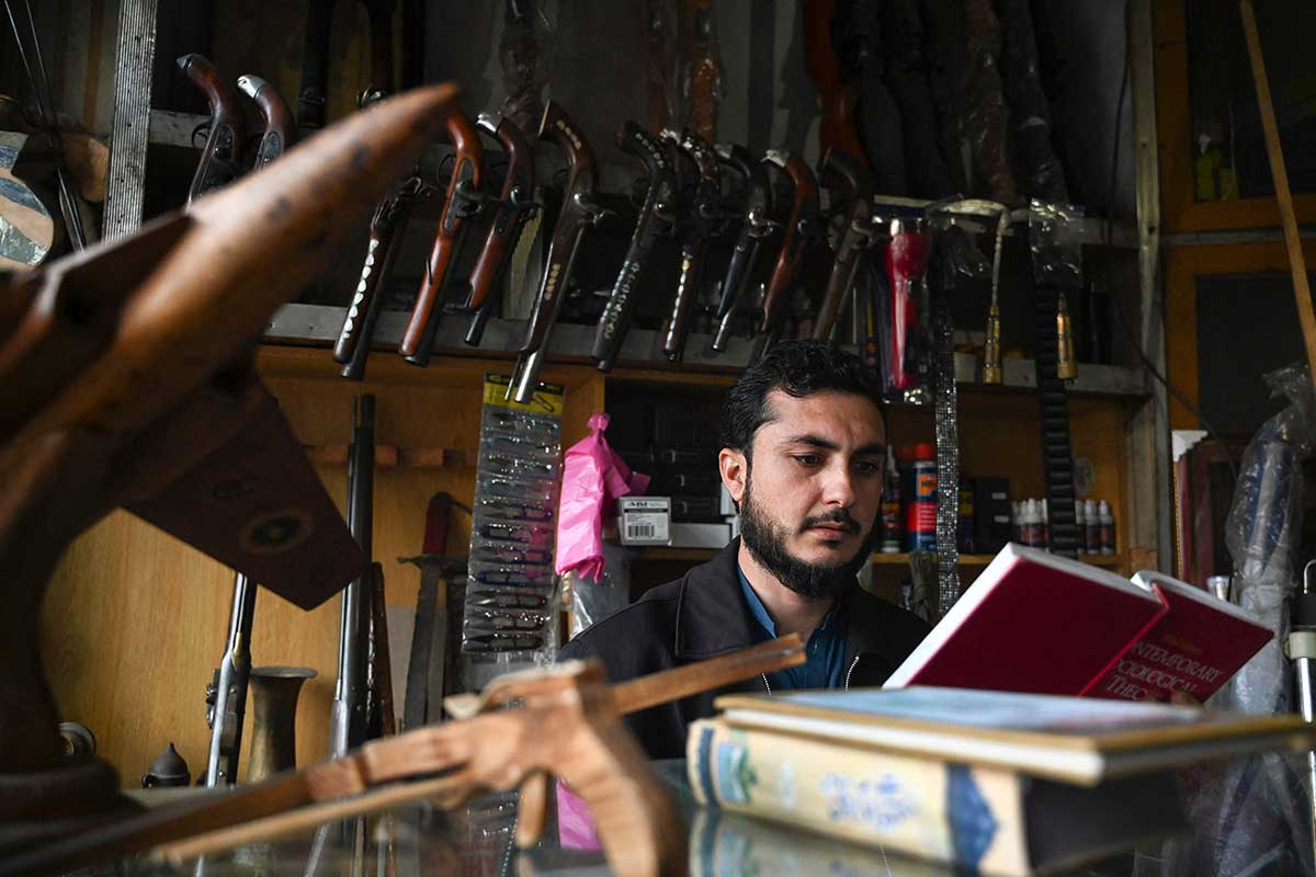 Pedagang senjata Muhammad Jahanzeb membaca buku di tokonya di kota Darra Adamkhel.  —AFP