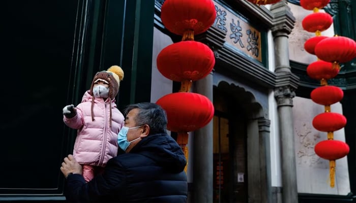 An elderly person holds a child near lanterns decorating a shop ahead of the Chinese Lunar New Year, in Beijing, China, January 15, 2023.— Reuters