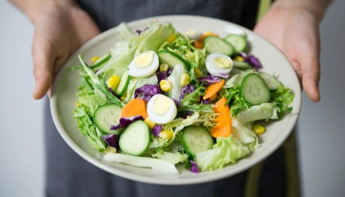 A person holding a bowl of vegetable salad.— Pexels