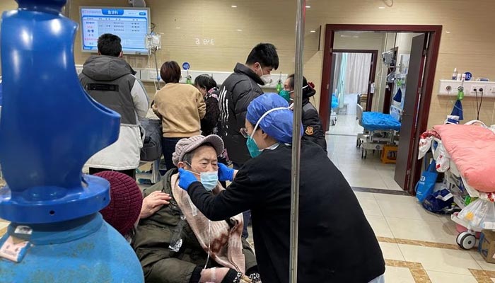 شنگھائی، چین میں 17 جنوری 2023 کو کورونا وائرس کی بیماری (COVID-19) کے پھیلنے کے درمیان، ایک طبی کارکن ہسپتال کے ایمرجنسی ڈیپارٹمنٹ میں علاج حاصل کرنے والے مریض کی مدد کر رہا ہے۔ — رائٹرز