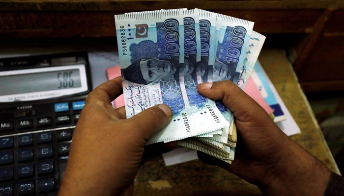 A trader counts Pakistani rupee notes at a currency exchange booth in Peshawar, Pakistan December 3, 2018. — Reuters