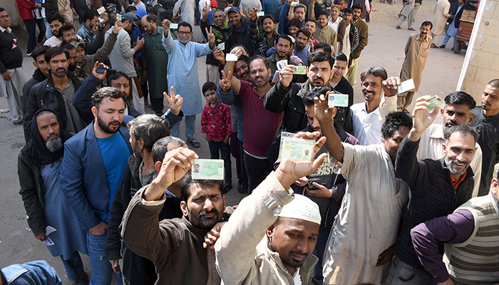 Voters stand in a queue outside a polling station to cast their ballots during local government elections, in Karachi on January 15, 2023. — Online