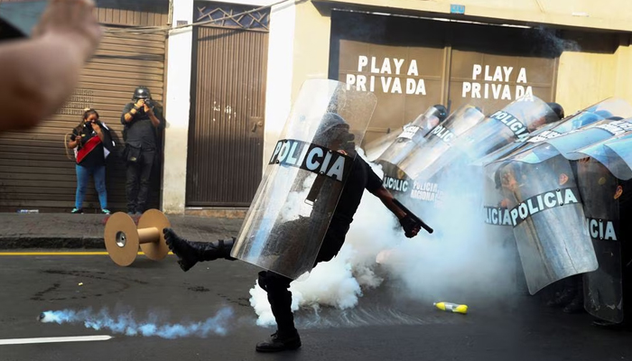 Seorang petugas polisi anti huru hara menendang kaleng gas air mata selama pawai Take over Lima untuk berdemonstrasi menentang Presiden Peru Dina Boluarte, menyusul penggulingan dan penangkapan mantan Presiden Pedro Castillo, di Lima, Peru 19 Januari 2023.— Reuters