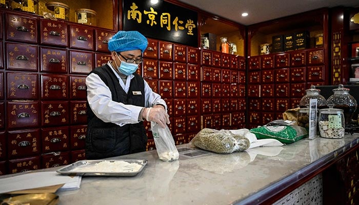 Foto yang diambil pada 23 Desember 2022 itu memperlihatkan seorang pekerja medis yang bekerja di apotek obat tradisional Tiongkok di Beijing.  —AFP