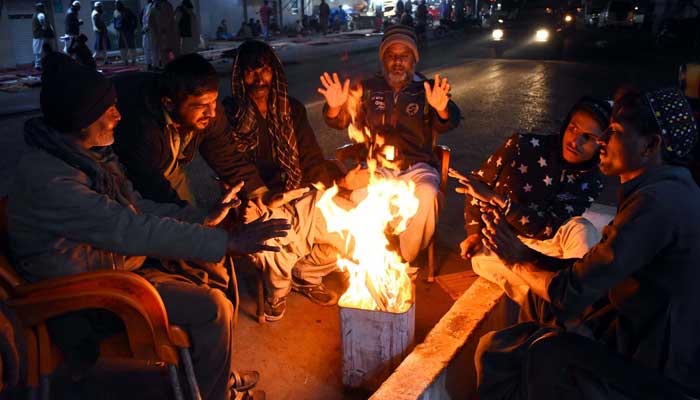منگل، 31 دسمبر، 2019 کو کراچی میں سردی کے موسم میں سردی کی لہروں سے خود کو بچانے کے لیے لوگ الاؤ پر ہاتھ گرم کر رہے ہیں۔ - PPI