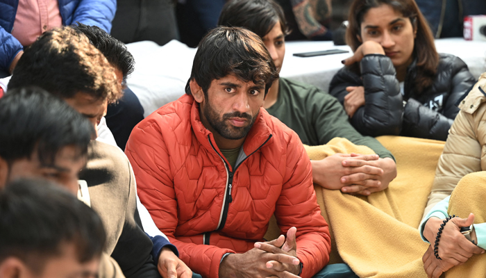 Pegulat India Bajrang Punia (berbaju merah) dan Vinesh Phogat (kanan atas) ambil bagian bersama pegulat lainnya dalam protes berkelanjutan terhadap Federasi Gulat India (WFI), di New Delhi pada 19 Januari 2023.— AFP